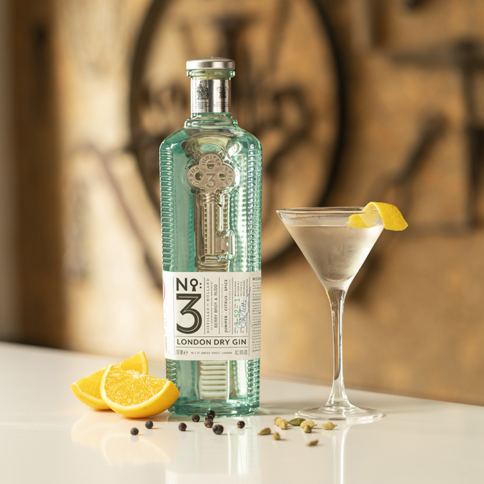 A photo of our No.3 London Dry Gin, alongside a gin cocktail, slices of orange, juniper berries and cardamom, which are a few of the key ingredients in our spirit