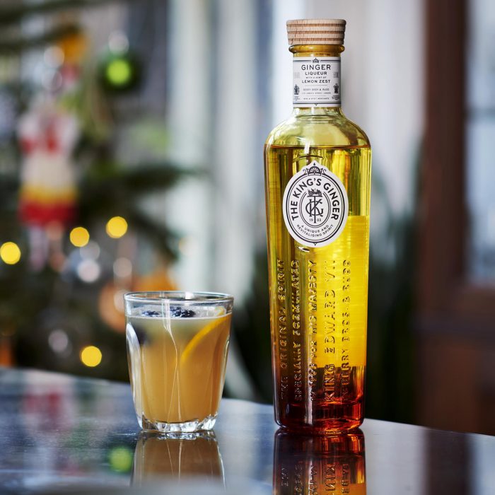 A bottle of the newly redesgined King's Ginger stands next to a small mulled cocktail