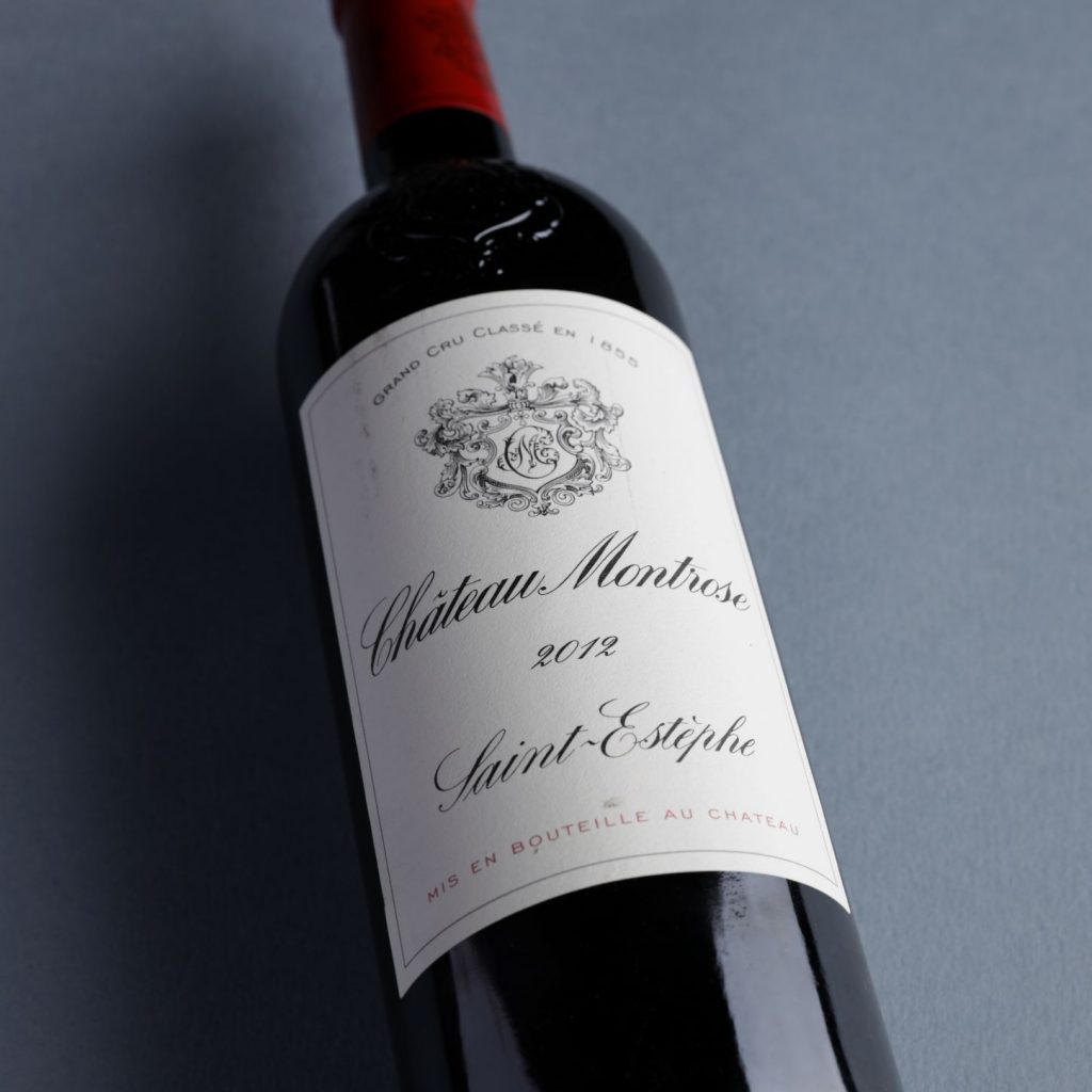 A bottle of 2012 Ch. Montrose is photographed against a dark grey background