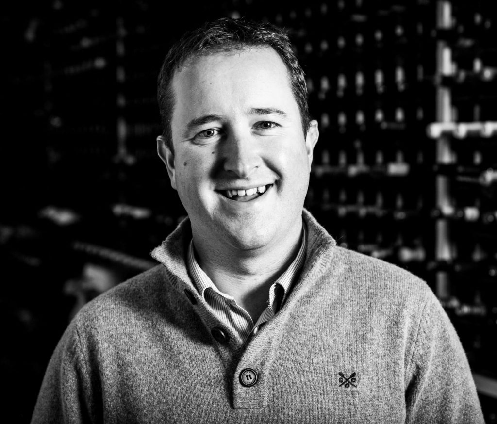 Martyn Rolph, Commercial Manager at Berry Bros. & Rudd, photographed in black and white in a wine warehouse. 