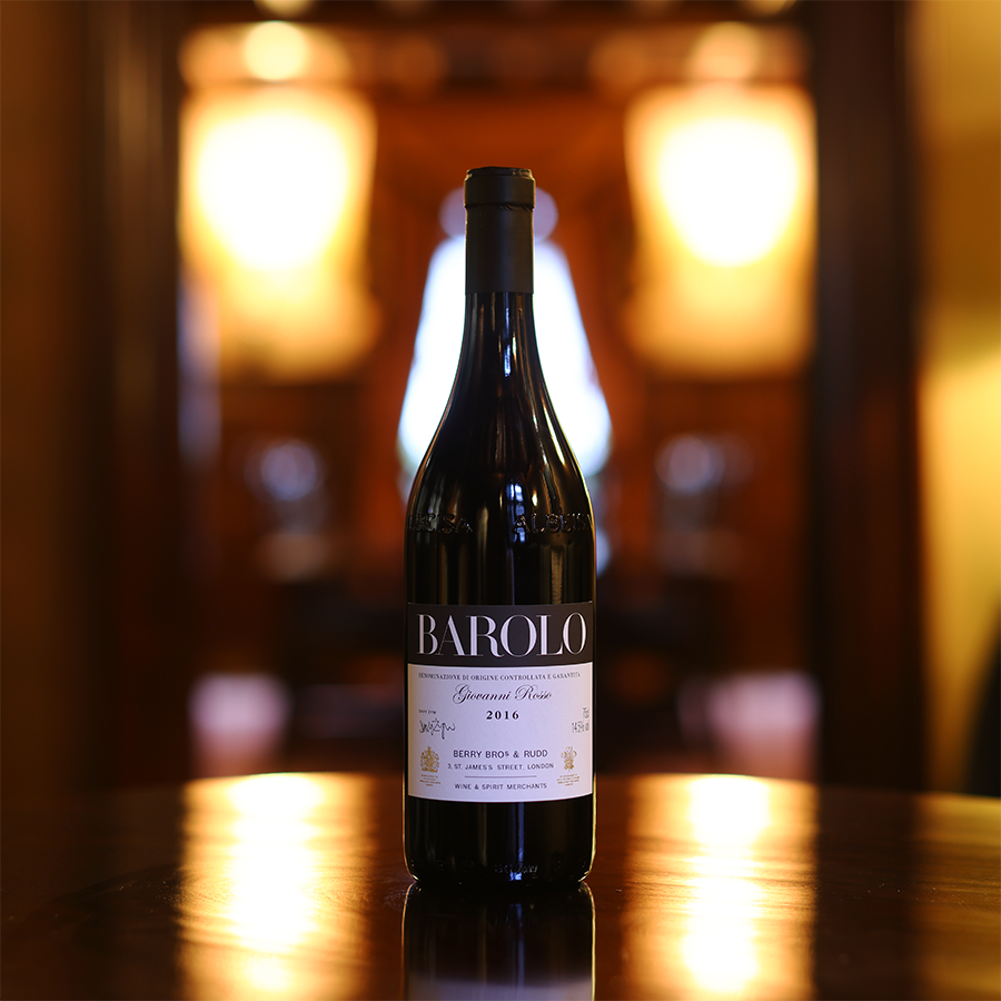 A photograph of our Own Selection Barolo sitting atop a gleaming polished table in a softly lit room. 