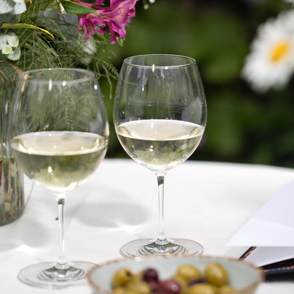 Two glasses of white wine on a table outside.